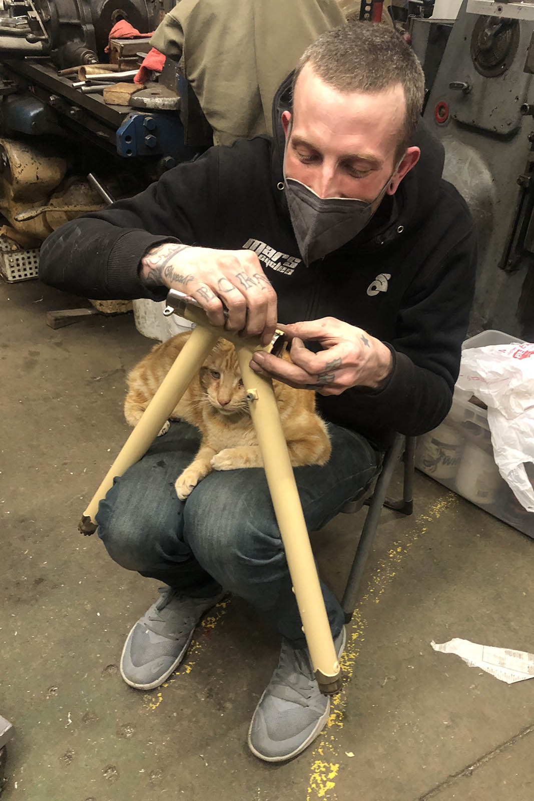 casey sussman working on a frame with a cat in his lap