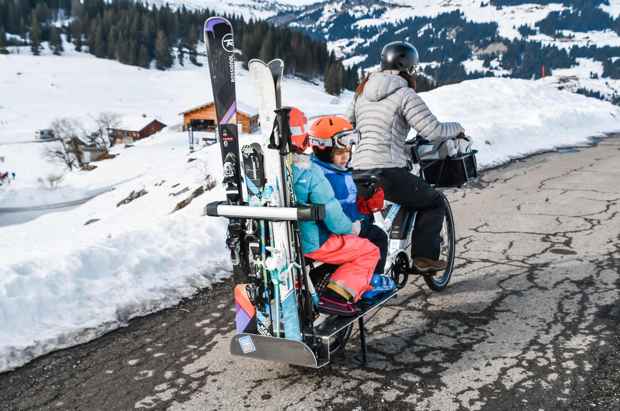 Photo of Yuba bike loaded with two children, a rider and skis for the whole family. Rear view.