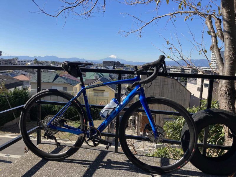 bikerumor pic of the day mt fuji in the background of the city of fujisawa japan with a fuji bicycle in the foreground, the sky is clear bright and blue.