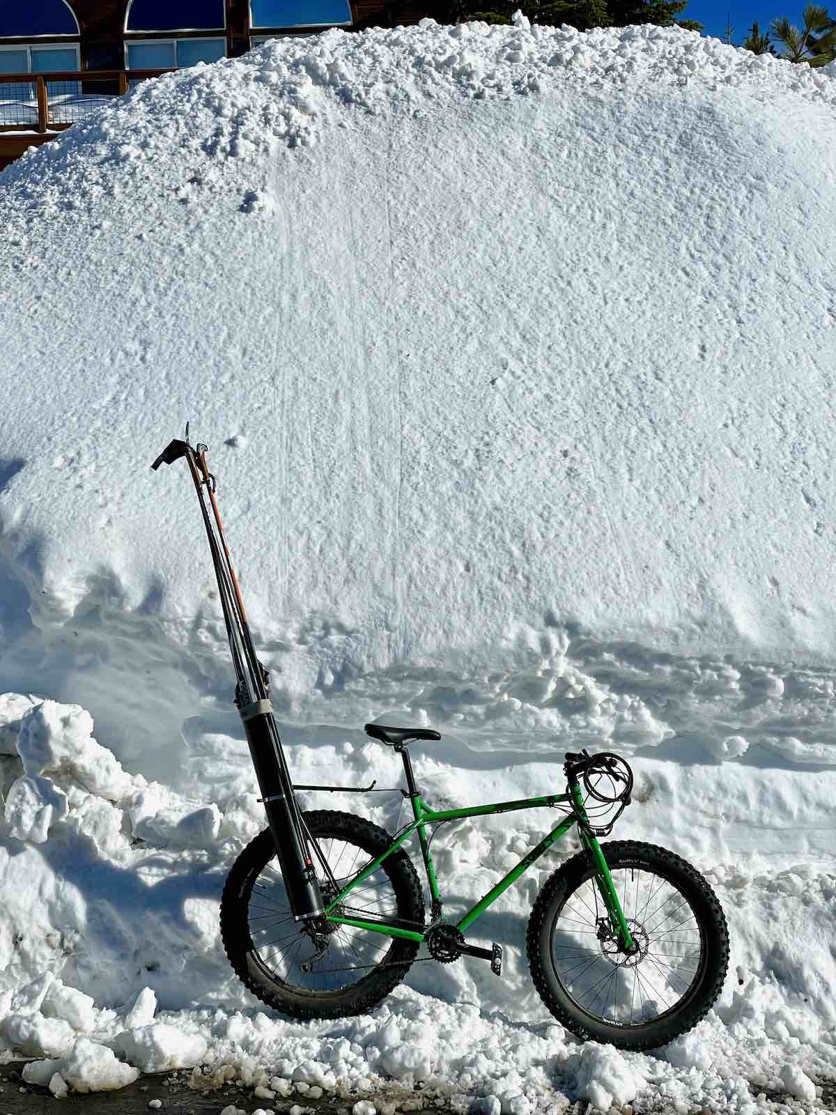 bikerumor pic of the day a fat bike with skis in a pack on the back sits next to a giant pile of snow.