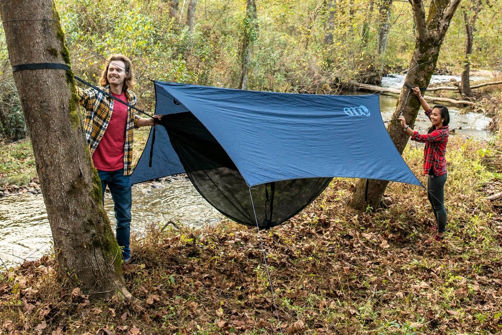 A couple mounts and ENO hammock to trees in a forest.