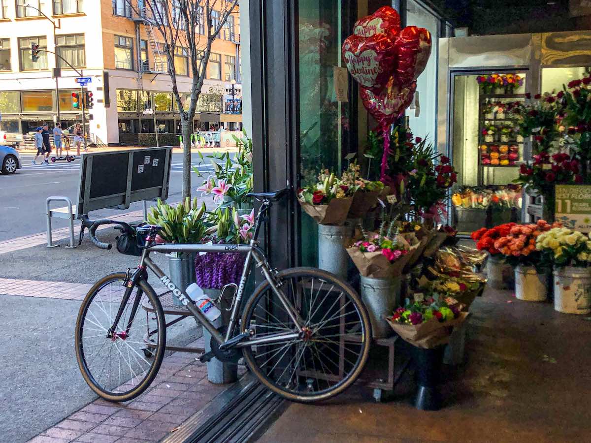 bikerumor pic of the day a moots titanium bicycle is positioned at the entrance to a flower store that opens on to the street in san diego california. there are buckets of flowers on the floor and heart shaped balloons for sale for valentines day.