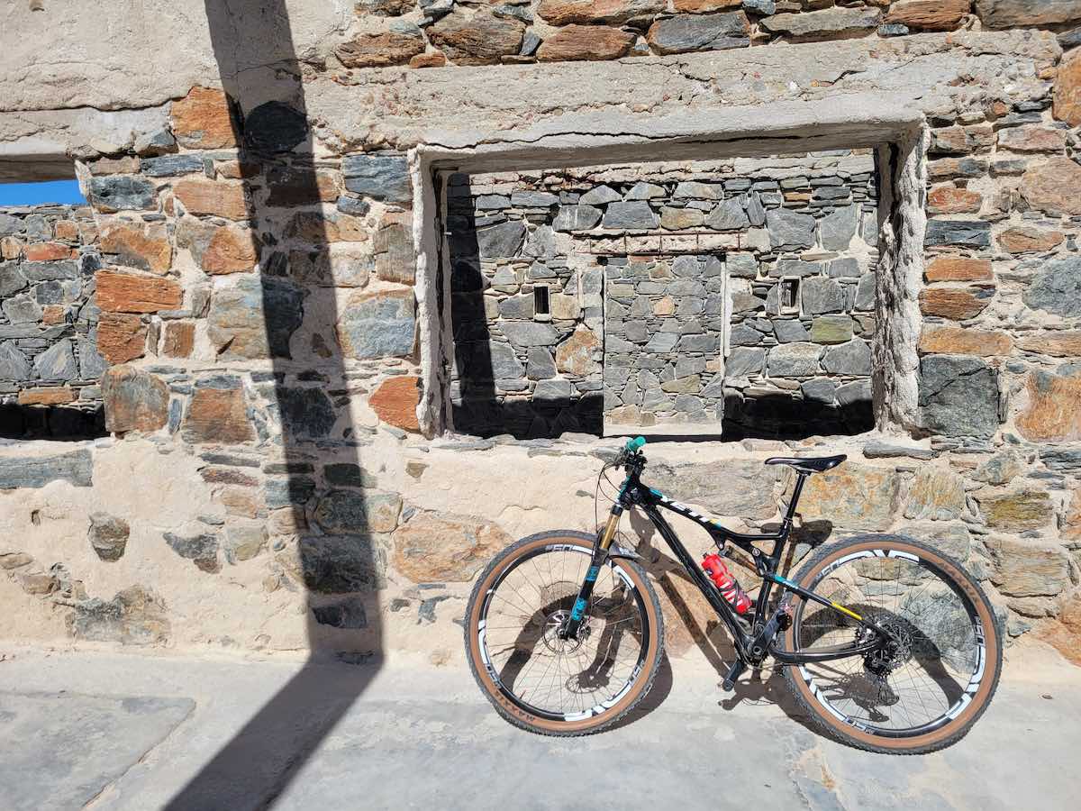 bikerumor pic of the day a bicycle leans against a large stone wall, the day is sunny and bright.