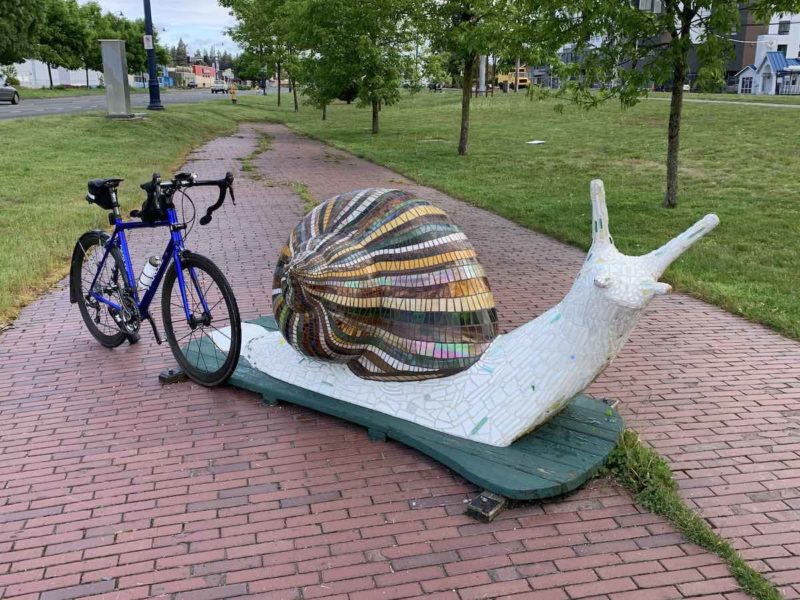 bikerumor pic of the day a bicycle is positioned near the rear of a large statue of a snail the title of the photo is drafting
