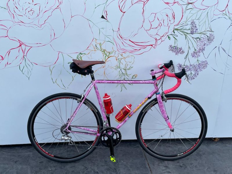 bikerumor pic of the day a pink road bike is positioned next to a white wall with pink outline drawing of flowers.
