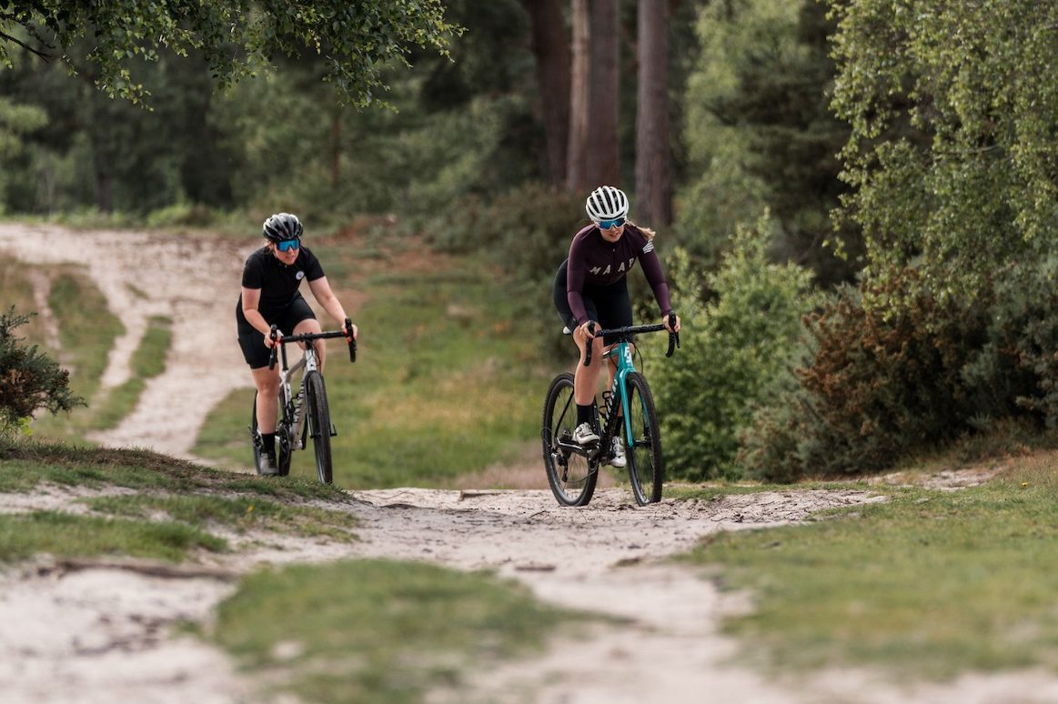 Two cyclists riding on a gravel path.