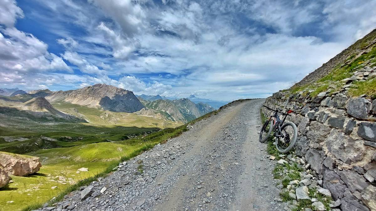 bikerumor pic of the day a bicycle leans against the the high side of a mountain next to a gravel road looking out over a green valley.