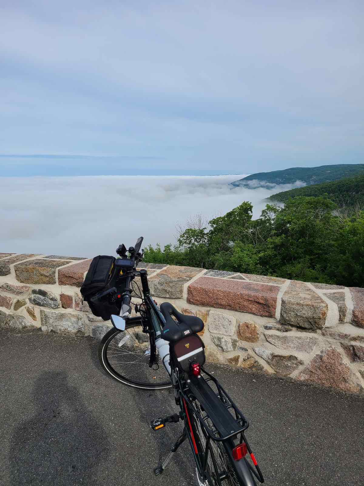 bikerumor pic of the day a bicycle is on an overlook with a stone wall looking out over a large fog covered area with trees peeking out on the right side.