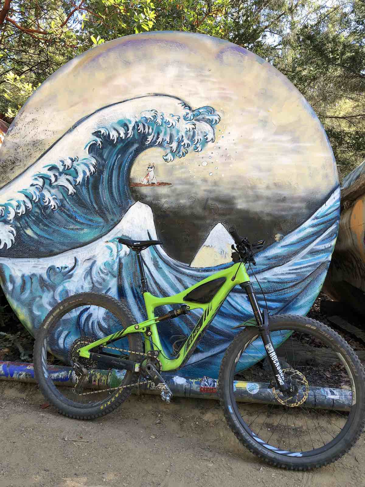 bikerumor pic of the day a lime green mountain bike leans against a mural of a wave painted in the japanese wood block style.