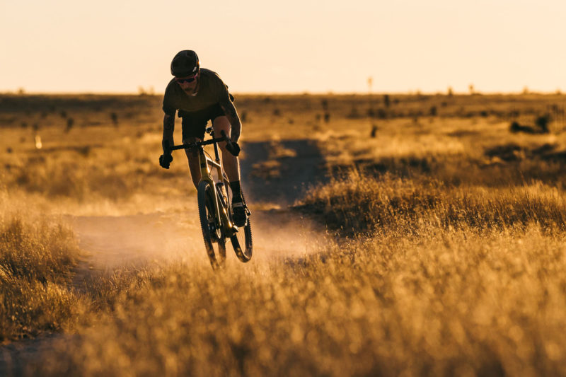 riding action on reserve 25GR gravel bike wheels in a golden field