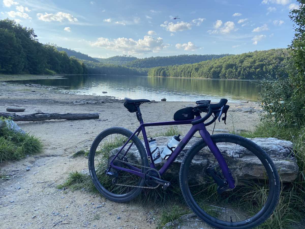 bikerumor pic of the day a lauf bicycle leans against a rock on a sandy beach near a lake surrounded by forest