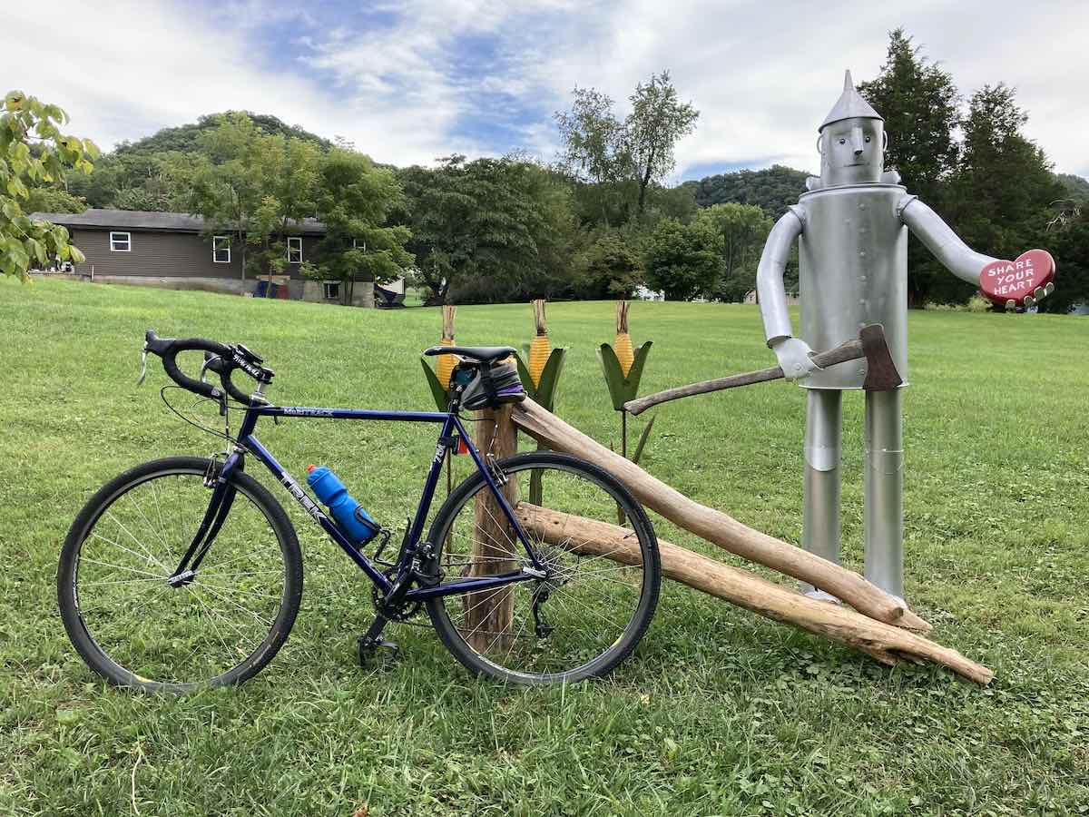 bikerumor pic of the day a gravel bike leans against a split wood fence in a green grassy field next to a tin man and some corn
