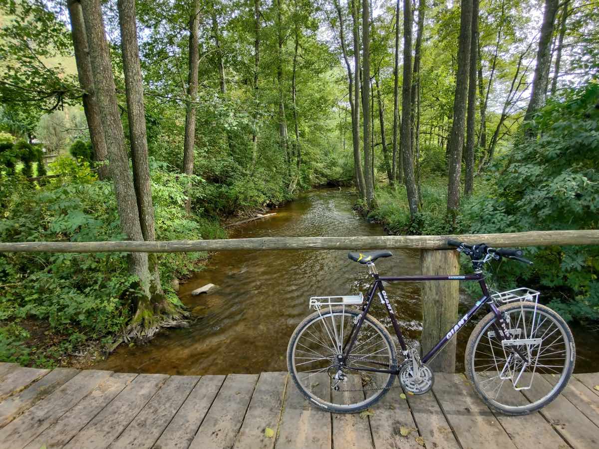bikerumor pic of the day a bicycle is on a wood bridge crossing a wide stream in the middle of a forest in Suwalszczyzna region of poland.
