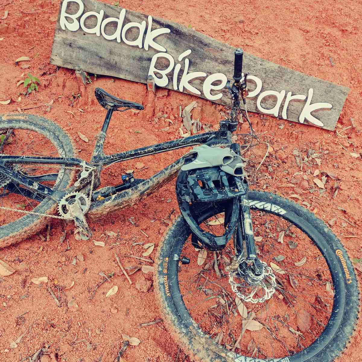 bikerumor pic of the day a mountain bike and helmet lay on the ground that is red dirt with some leaves and a wood sign for badak bike park