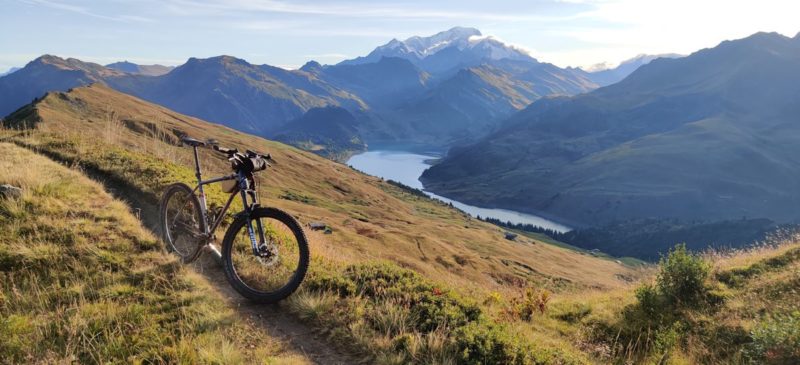 bikerumor pic of the day a mountain bike on the side of a grass field on a mountain bight a lake below and mont blanc in the distance