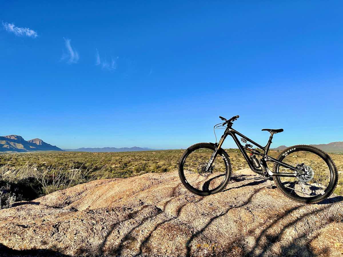 bikerumor pic of the day a bicycle is on a dirt outcropping in the middle of a wide expansive valley, the sky is clear and blue and there are low mountains in the distance.