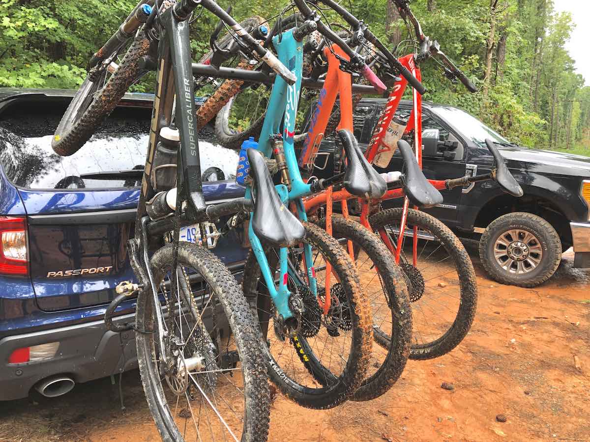 bikerumor pic of the day four mountain bikes hang off the bike rack of a car the tires are covered in red carolina soil.