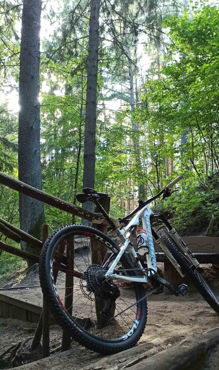 bikerumor pic of the day a mountain bike leans against the railing of a wood foot bridge in the middle of the woods.