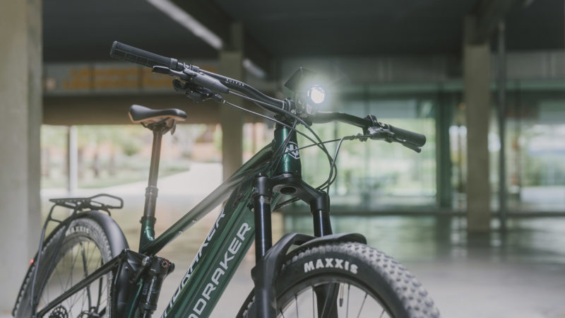 um close-up do CHASER RX mostrando sua suspensão de mountain bike, luzes e rack traseiro. 