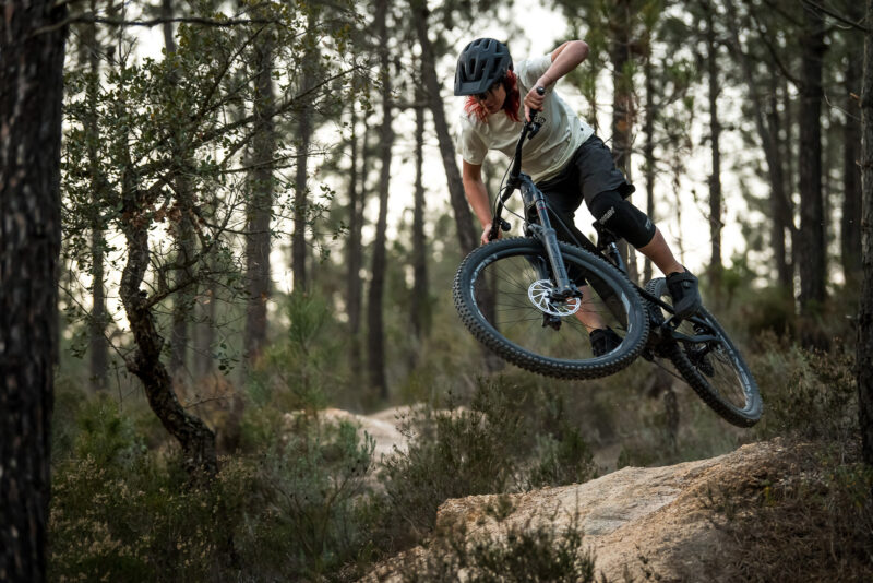 mountain biker riding propain tyee 2023 model jumping off rock girona spain forest