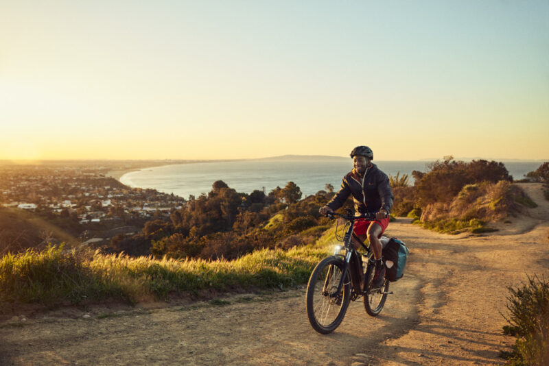a man riding an ebike on a trail during sunset