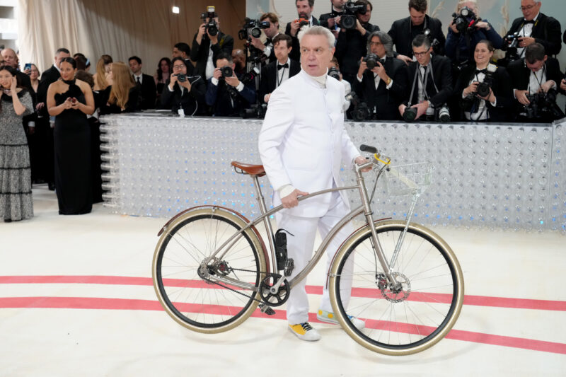 david byrne in a white suit with a bicycle