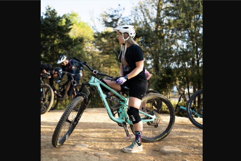 a woman standing over a mountain bike
