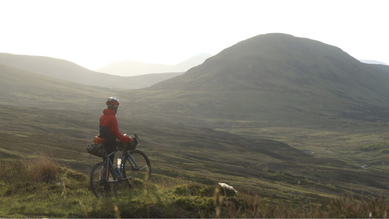 a man with a loaded bike stares out over Scotland