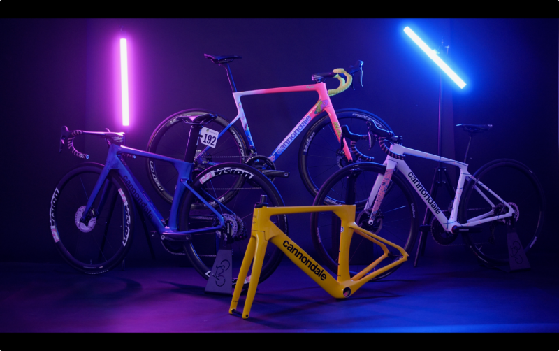 Four Cannondale team bikes from 2021 and 2022 with pink and blue neon lights behind them.