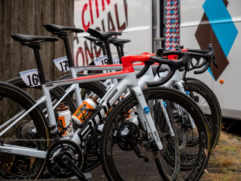 Six BMC AG2R's 2022 season bikes lined up next to a team bus.