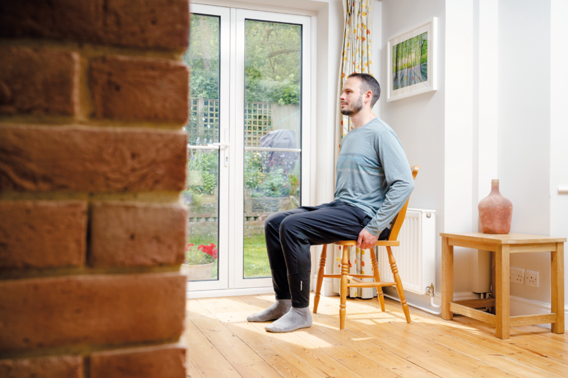 A man sitting on a chair to measure his sit bones with the SQlab home measurement kit.