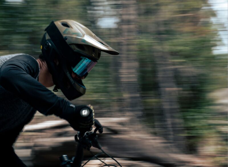A mountain bike riding in a MET Parachute MCR helmet with the chin bar attached. 