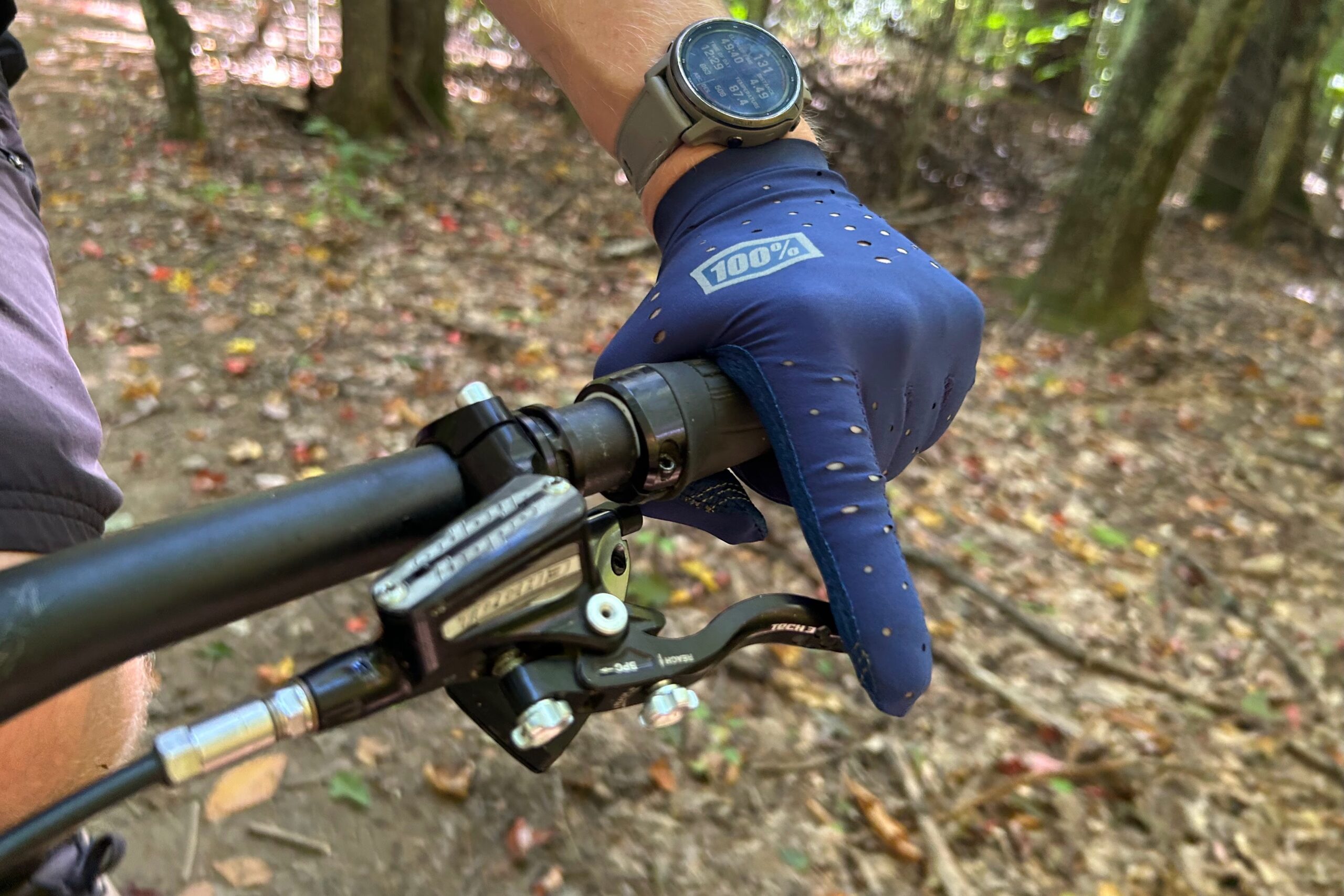 100 Sling mountain bike gloves holding a mountain bike grip