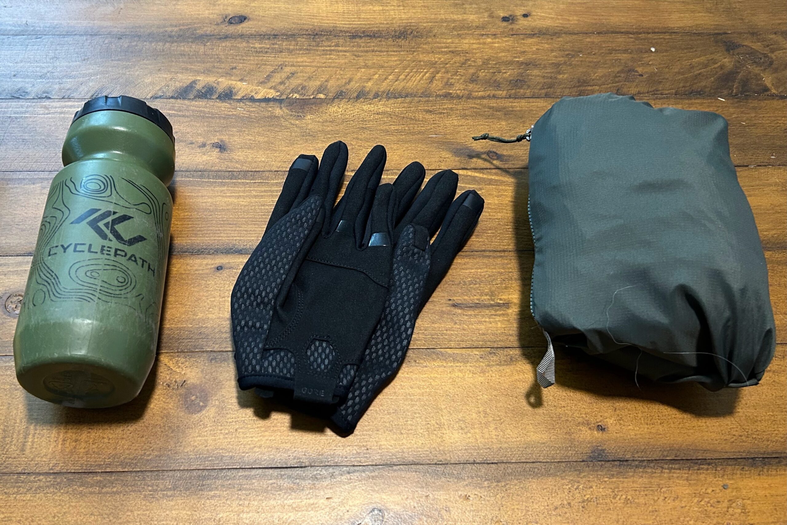The Patagonia Dirt Roamer mountain bike jacket packed into its pocket and compared to a pair of gloves and water bottle