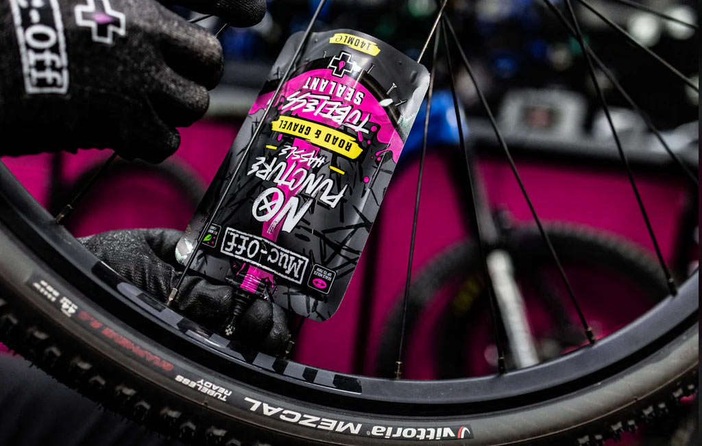 muc-off road and gravel tubeless tire sealant being squeezed into a valve stem.