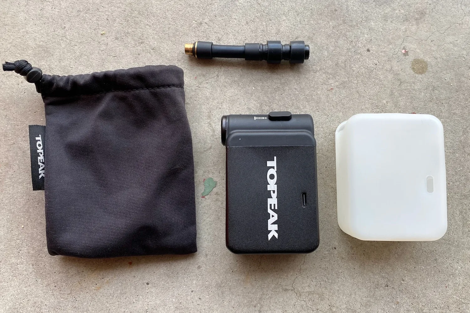 All the parts of the Topeak E-Booster Digital pump. The pump, silicone cover, extension hose, and storage bag