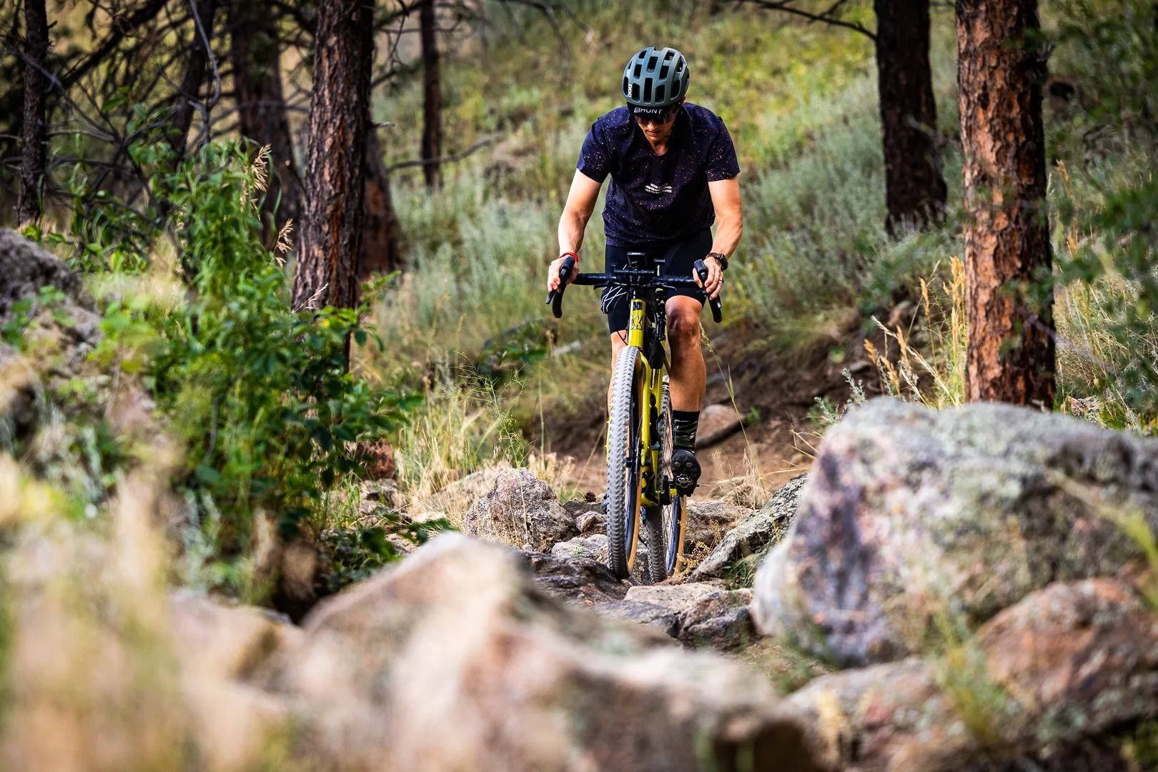 A rider on a gravel bike riding on a very rocky mountain bike trail.