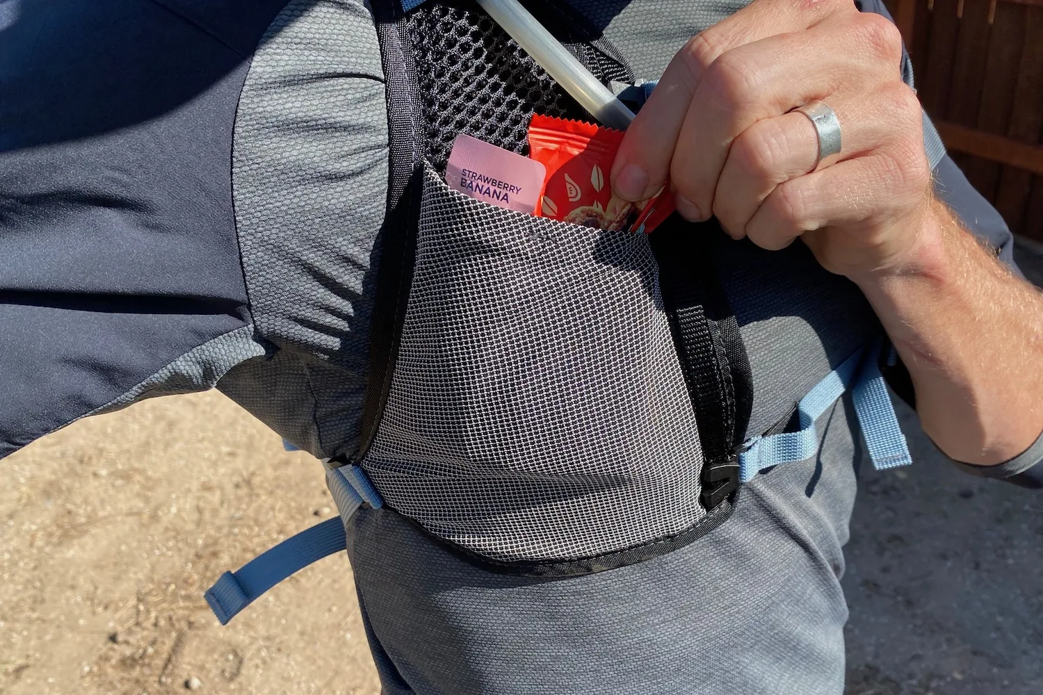 Pulling a snack out of the stretch pocket on the strap of the SuperNatural pack