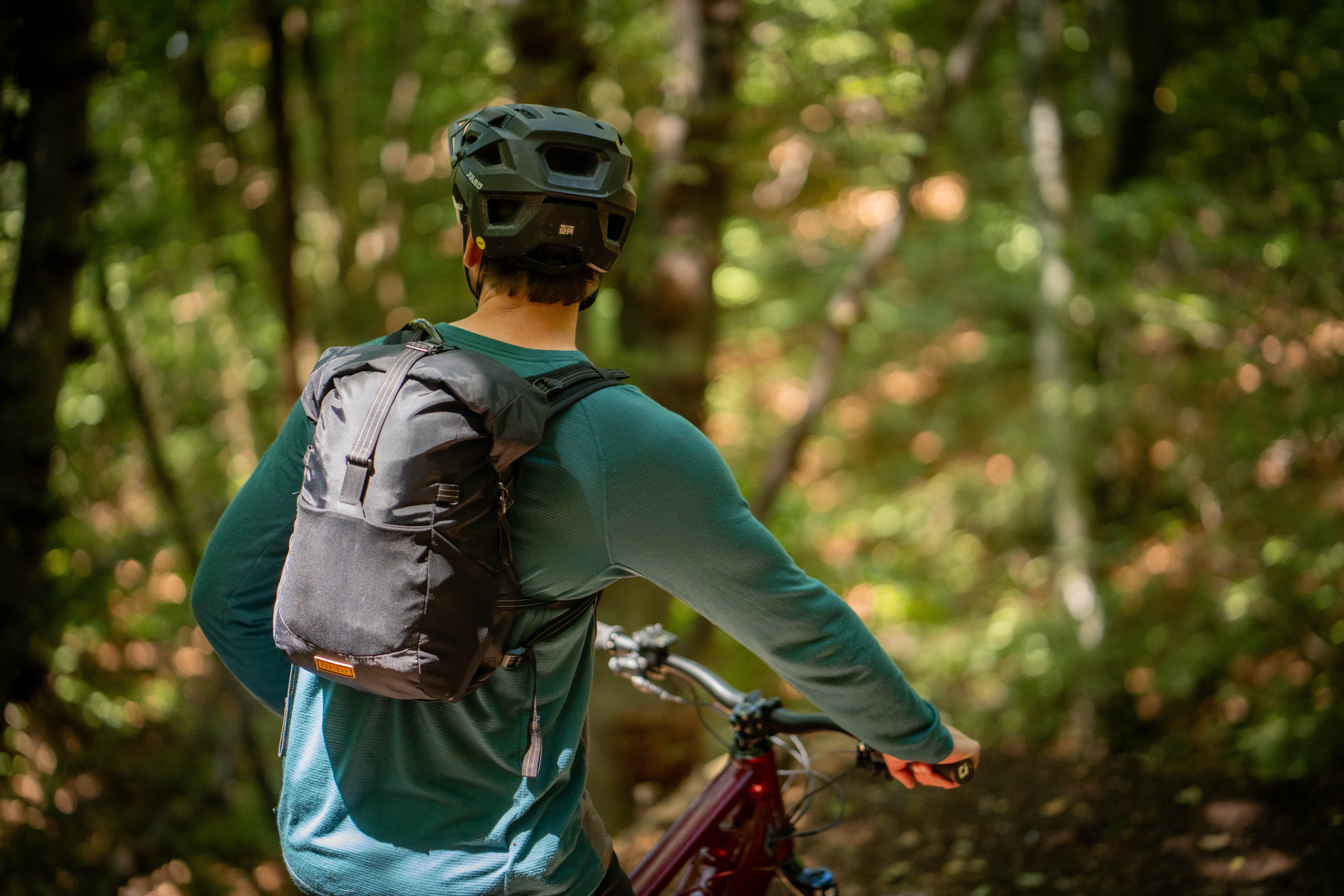 A mountain biker is stopped on a ride in the wilderness wearing a Restrap Rolltop Hydration Vest