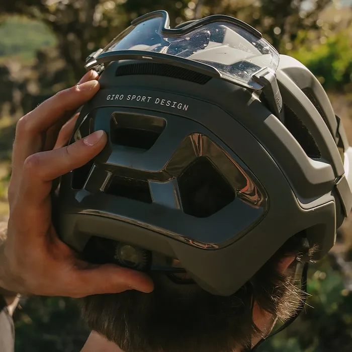 A rider adjusting the fit harness on the Giro Montaro Mips III with sunglasses stashed in the back vents, too.