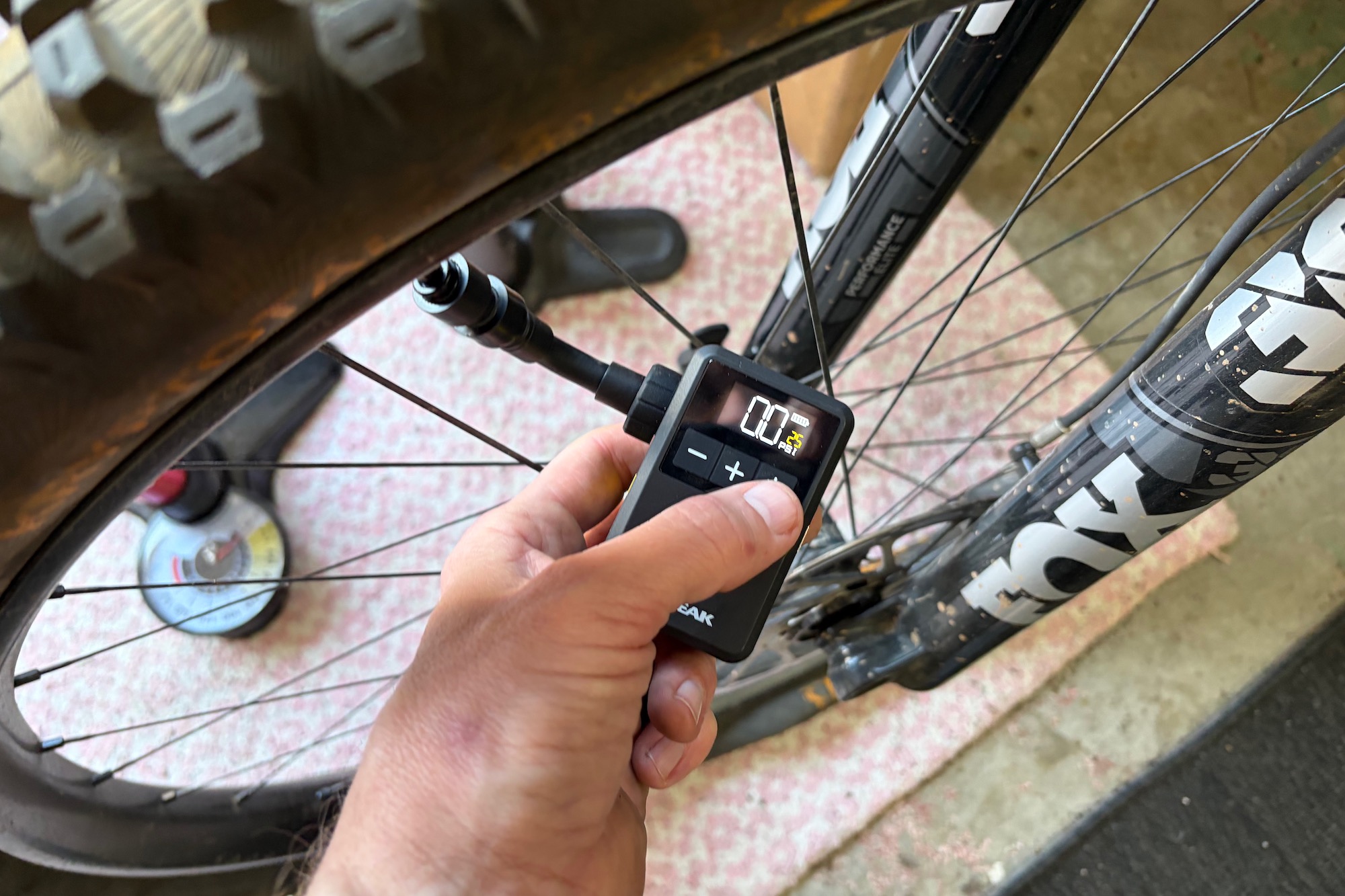 turning on the Topeak E-Booster Mini, attached to a mountain bike tire valve