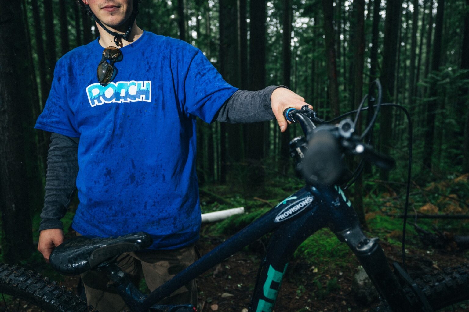 a guy wearing the roach classic t-shirt, standing in the woods with a bike.