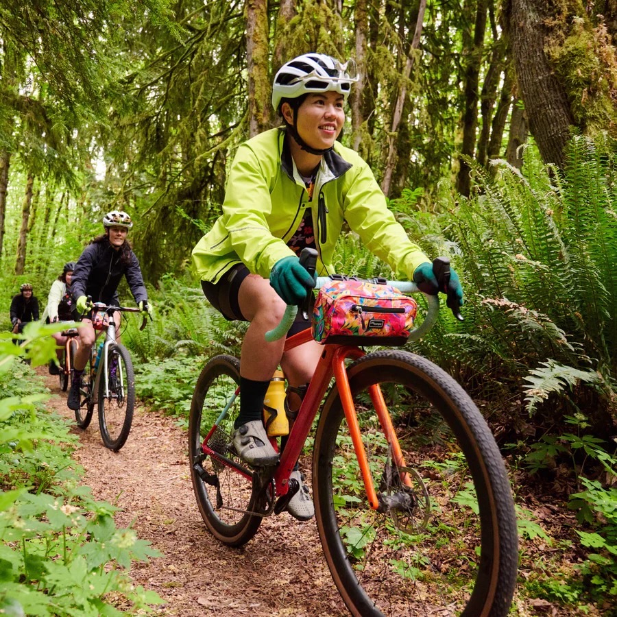 a woman riding in the Century Rain Jacket on a gravel bike