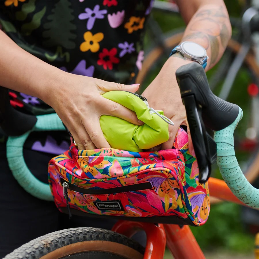 a person stuffing the Century Jacket into a handlebar bag.