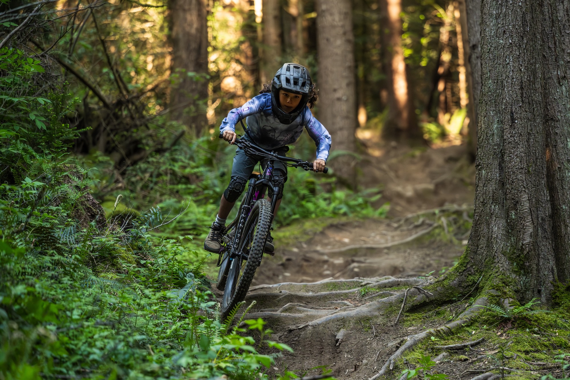 et barn, der kører på Process 246 ned ad en rodfæstet mountainbikesti