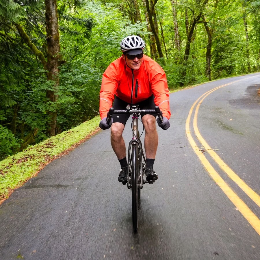 a man riding in the showers Pass century jacket
