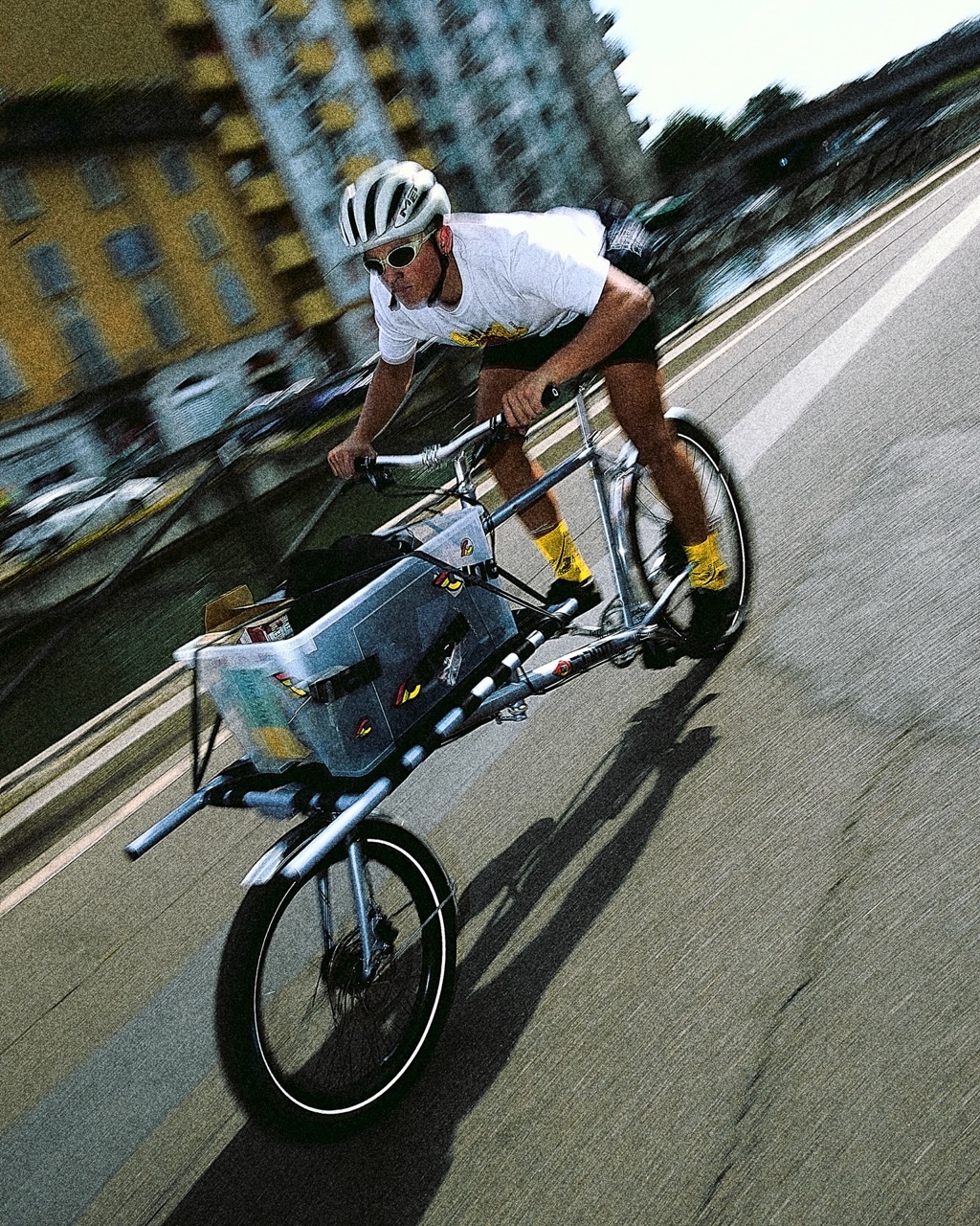A rider with cargo on the front rack of the OMNIUM x Cinelli Supercargo bike riding through the city streets