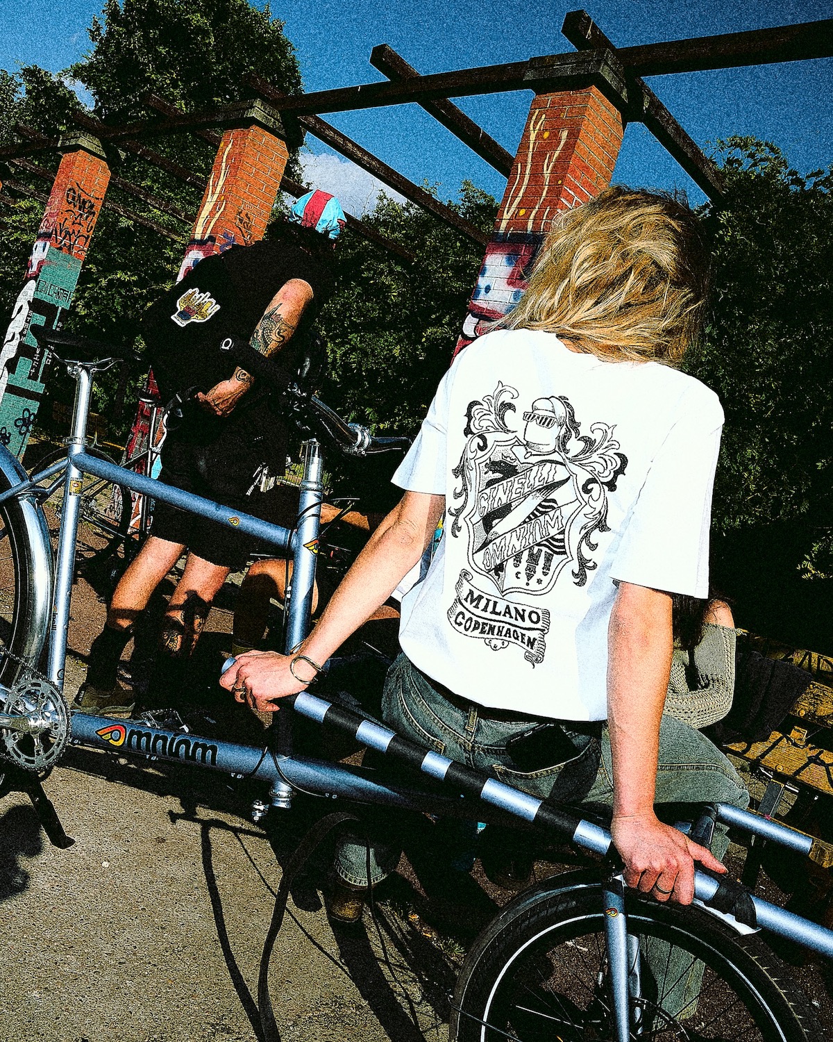 a person sitting on the front rack of the Omnium x Cinelli Supercargo bike wearing one of the limited edition t-shirts.