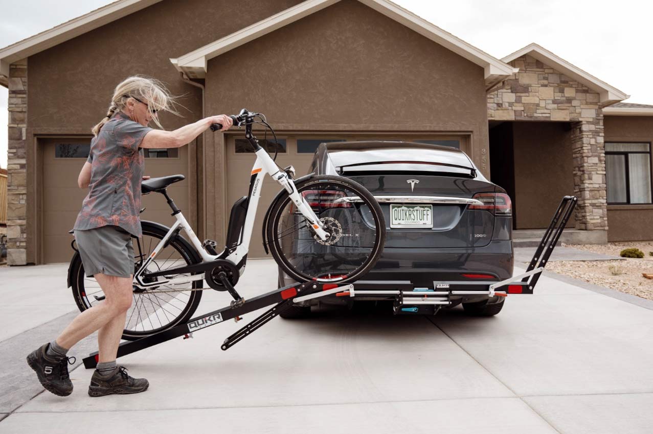 lady rolling e-bike onto QuikrStuff hitch bike rack using integrated ramp.