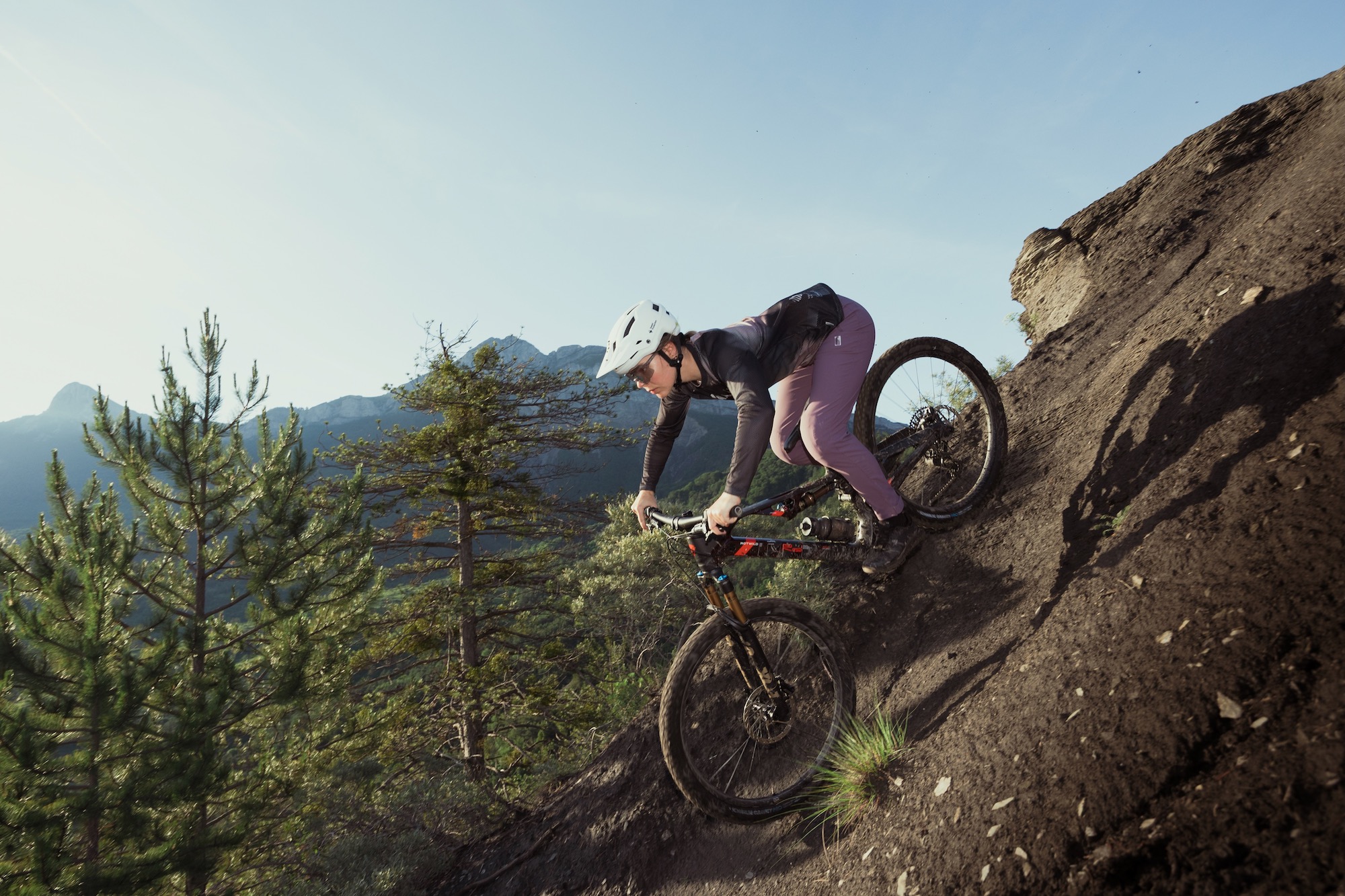 a female riding riding the Rotwild R.XX eMTB over a steep roll.